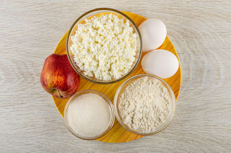 Ingredients for cooking of cottage cheese casserole with apples in bamboo plate on wooden table. Top viewの写真素材