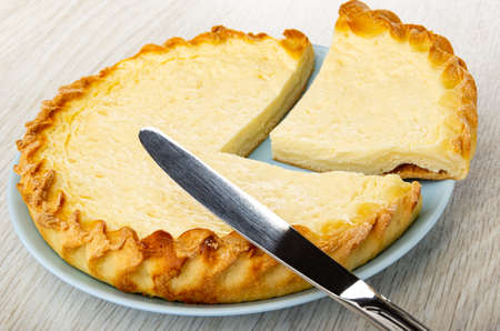 Table knife on pieces of sour cream pie in blue plate on wooden tableの写真素材