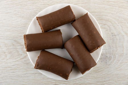 Few creamy bars with cocoa and peanut in white plate on wooden table. Top viewの写真素材