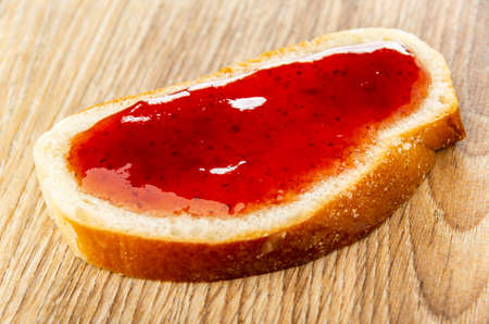 Sandwich from sweet bun with strawberry jam on wooden table