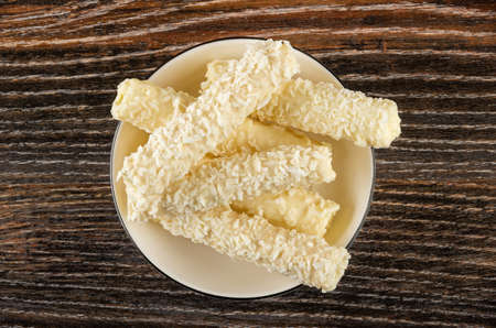 Candy with cream filling in coconut shaving in white glass bowl on dark wooden table. Top viewの写真素材