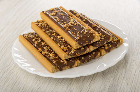 Few cookies with caramel, cocoa and cereals in white plate on light wooden table