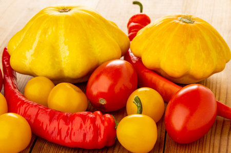 Heap of various vegetables, pattison, chili peppers, red and yellow tomatoes on wooden tableの写真素材