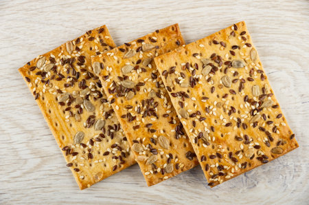 Three dry cookies with sunflower seeds, flaxseeds and sesame on wooden table. Top view