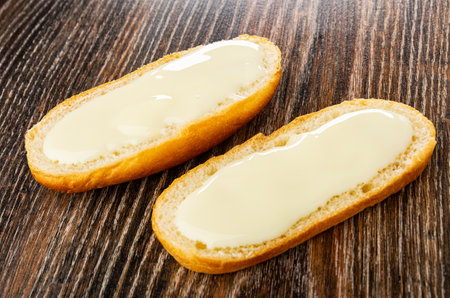 Two sandwiches with sweet condensed milk on dark wooden tableの写真素材