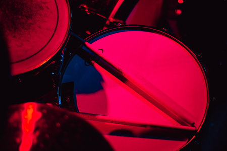 Drum kit close-up in neon light. Live music concept. snare drum, drumsticks, cymbals shiny reflectionsの写真素材