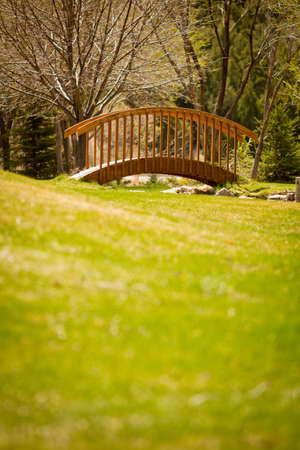 Bridge over small stream with grass field in front の写真素材