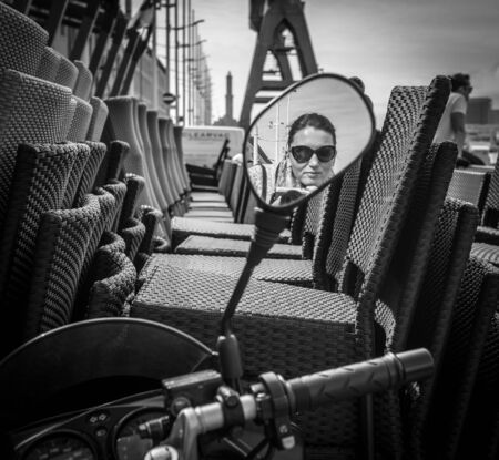 Sunglasses dressed female driver reflected in the street scooter rear view mirror imageのeditorial素材