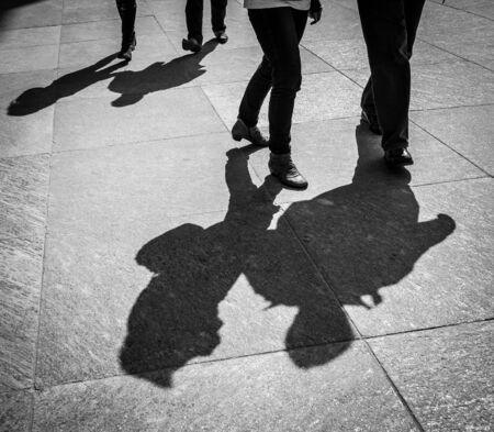 Couple walks by the paved italian street contrast shadow image      in Milan, Italy