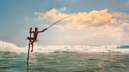 Sri lanka traditional stick- method fish catching Fisherman in the Indian Ocean waves.