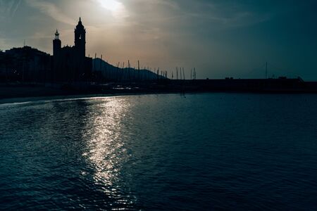 Early morning view of the coast in Sitges town near Barcelona in Catalonia,Spain with Parroquia de Sant Bartomeu i Santa Tecla church.の写真素材