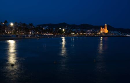Night view of the coast in Sitges town near Barcelona in Catalonia,Spain with Parroquia de Sant Bartomeu i Santa Tecla church.の写真素材