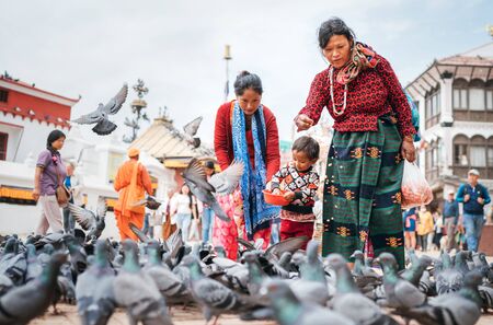Kathmandu, Nepal - October 20, 2019: Portrait of colorful dressed nepali family feeding a pigeons on the square near Boudhanath, Kathmandu, Nepal.のeditorial素材