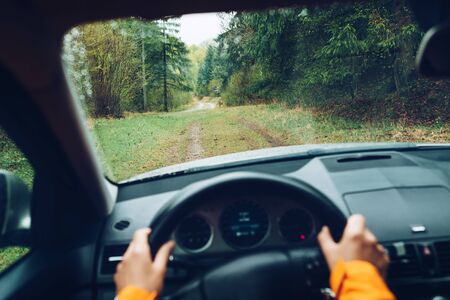 Driver dressed bright orange jacket driving a modern off road left hand drive LHD car on the...