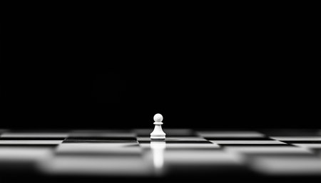 Black and White Chess Board scene with single white pawn with black background. Graphical minimalism concept photo with big copy space.の素材