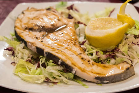 A slice of grilled swordfish on salad bedの写真素材