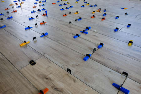 Installation of wood-style porcelain tiles on a floor. The colorful plastic spacers have the...