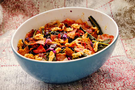 A dish of "panzanella" in winter version, with brown bread, pumpkin, speck, black and red cabbage, dried tomatoes and walnuts.の写真素材