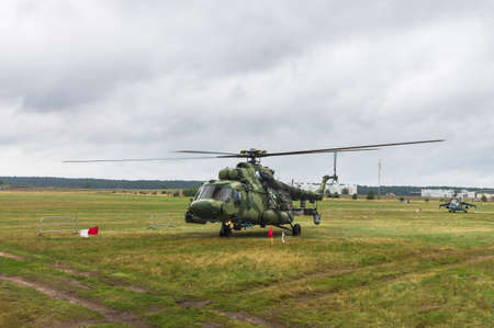 Military helicopter preparing to take off from grassy field on the background of the cityの写真素材