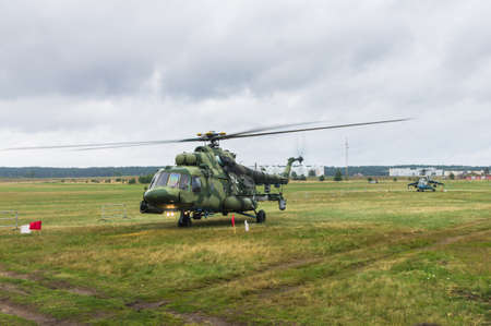 Military helicopter preparing to take off from grassy field on the background of the cityの写真素材