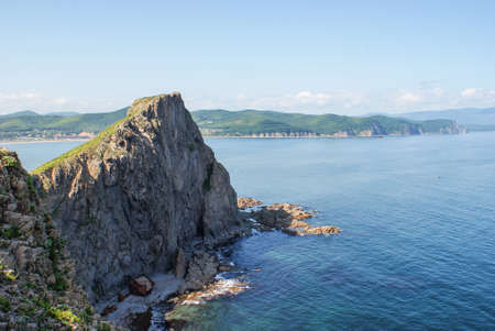 An old shipwrecked ship stands on the shore at the foot of a rocky cliff. Cape Briner. Primorsky Krai. Russia.の写真素材
