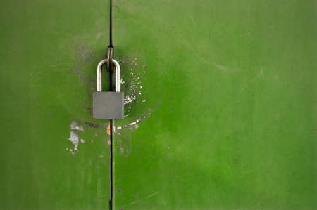 Green old metal door with the hinged padlockの写真素材