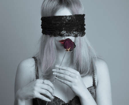 Studio portrait of a girl with dry rose and blindfoldedの写真素材