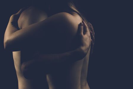 nude couple on a dark background hugsの写真素材