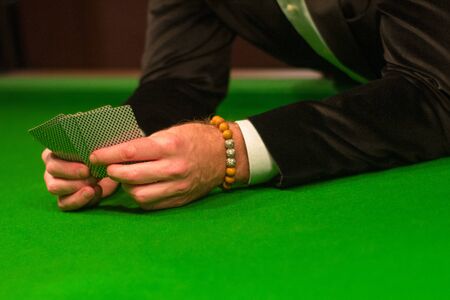 Playing cards in a man's hands on a green table. Close up.の写真素材