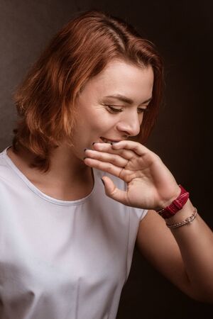 the girl laughs, covering her lips, her mouth with the back of her hand.