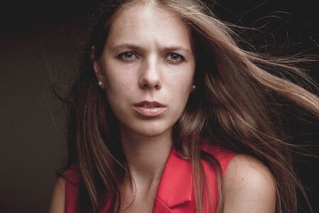 Girl portrait of beauty and fashion on a dark background in a red suit