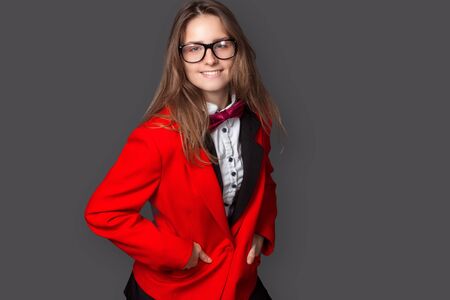 Young girl in white shirt, black vest and red jacket with Burgundy bow tie and classic black pants...