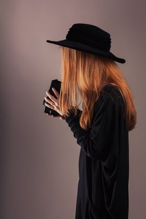 girl photographer in a black hat and clothes with an old camera in his handsの写真素材