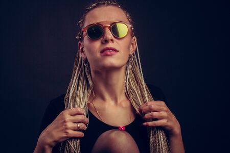 Fashion studio shoot woman sunglasses. with a creative colorful hairstyle in the form of a pigtail...