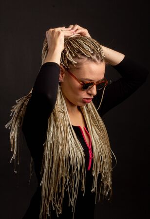 Fashion studio shoot woman sunglasses. with a creative colorful hairstyle in the form of a pigtail braided from dreadlocks Afro-pigtails in the technique of zizi. in motion air dancingの写真素材