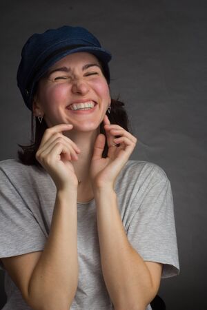 portrait of a brunette in a gray t-shirt and blue denim cap