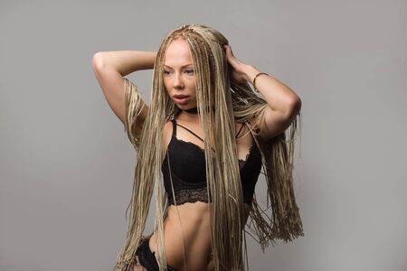 Fashion studio shoot woman with a creative hairstyle in the form of a pigtail braided from dreadlocks Afro-pigtails in the technique of zizi. in motion air dancingの写真素材