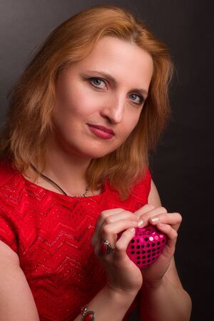middle-aged woman blonde Studio portrait. Holding a toy in the shape of a heart. concept of the Valentine's day love holiday.の写真素材