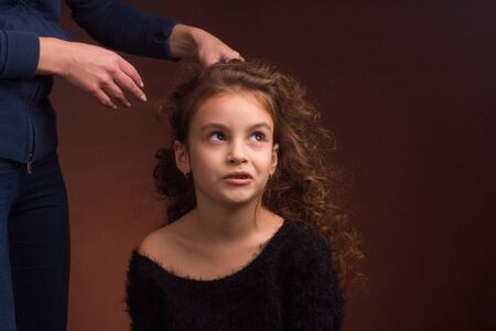 Studio portrait of a little girl, with a disgruntled face and curly curly hair, which women's...