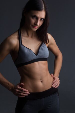 portrait of a brunette in a sports top and trousers on a dark background in the Studioの写真素材