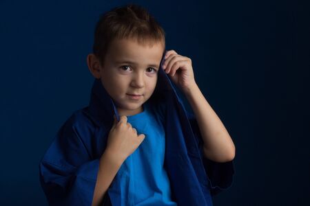 Studio portrait of boy in a blue classic sweater on a dark backgroundの写真素材