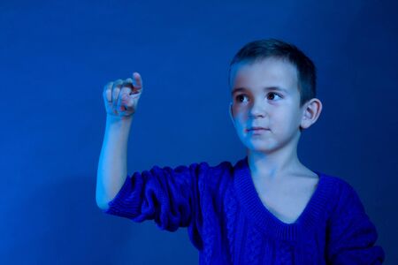 Studio portrait of boy in a blue classic sweater tinted in the coldの写真素材