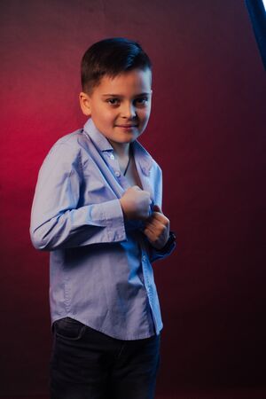 The Studio portrait of boy is a brunette, in a blue shirt on a purple and maroon background.の写真素材