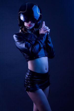 High Fashion model woman in underwear in colorful bright lights posing in studio, portrait of a beautiful girl. Artistic colorful design. Party concept, in underwear, leather jacket, jeans and motorcycle helmetの写真素材