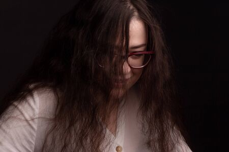 portrait of a plump brunette with long curly hair, in a white shirt, wearing glasses