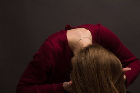 portrait of a girl in the Studio with painted blonde hair, in a red sweater. Warm toned. head down, face hiddenの写真素材