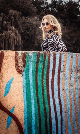 woman blonde in sunglasses, posing on a city streetの写真素材