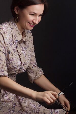 Photo woman with straight dark hair, posing in a shirt with painted flowers on dark background in Studioの写真素材