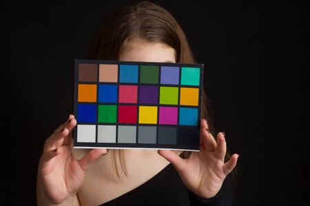 Portrait of girl in a black one-shoulder dress open, naked, in Studio on black background c calibration tableの写真素材
