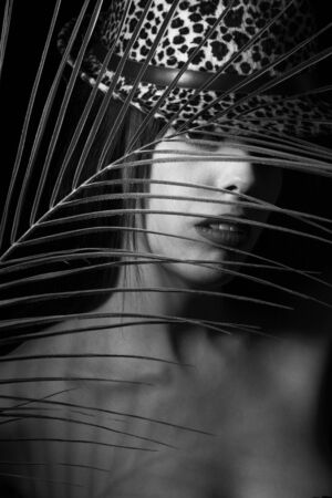 black and white portrait of a young woman with leaf palms. Studio photoの写真素材